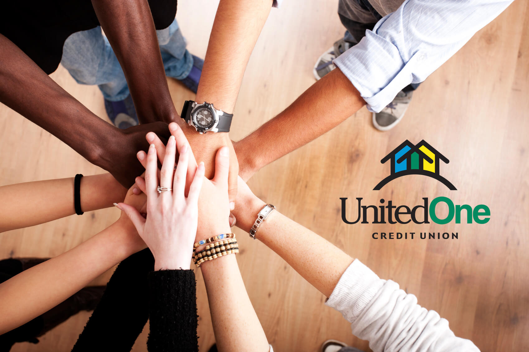 Group of people's hands as they huddle in a circle with UnitedOne Credit Union logo on the right.